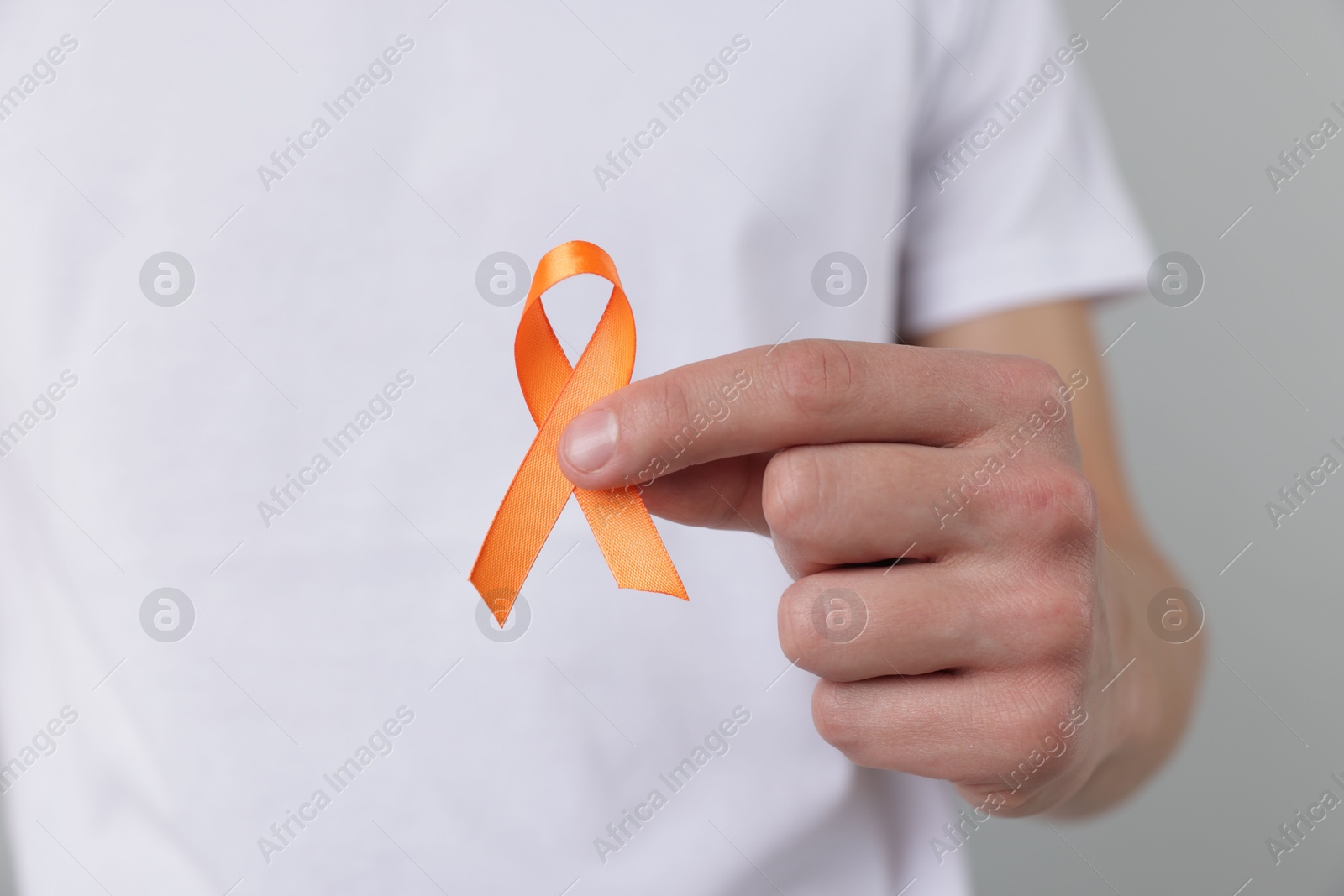 Photo of Multiple Sclerosis awareness. Man with orange ribbon on light grey background, closeup