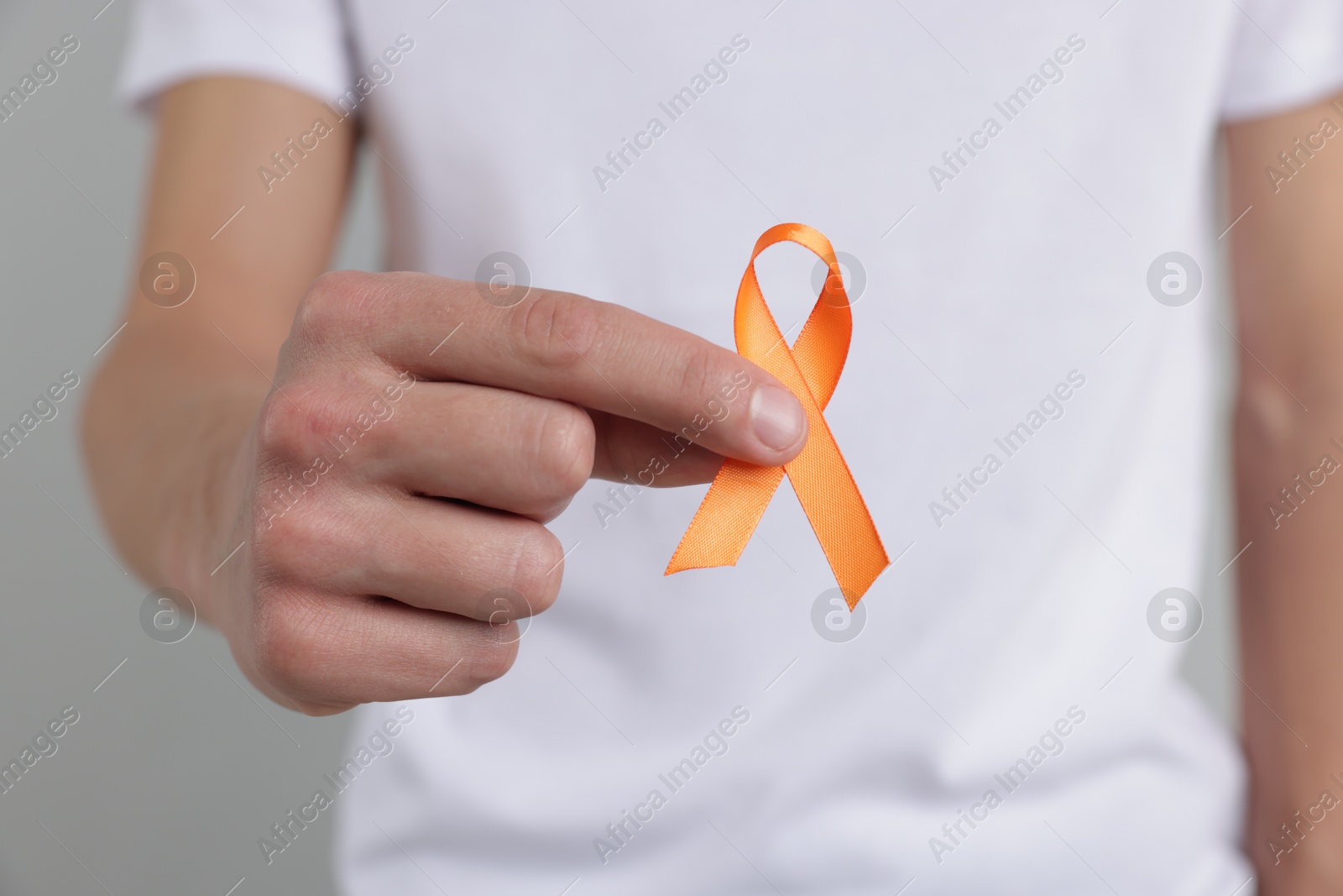 Photo of Multiple Sclerosis awareness. Man with orange ribbon on light grey background, closeup