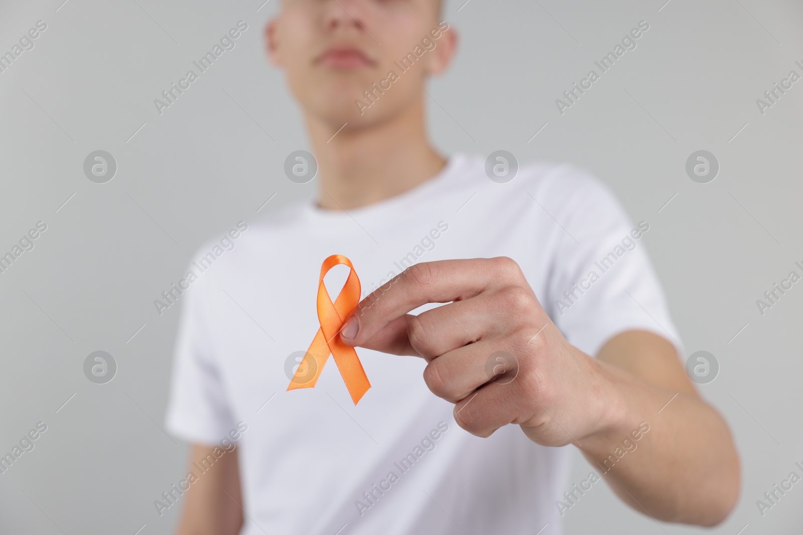 Photo of Multiple Sclerosis awareness. Man with orange ribbon on light grey background, closeup