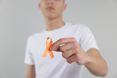 Photo of Multiple Sclerosis awareness. Man with orange ribbon on light grey background, closeup