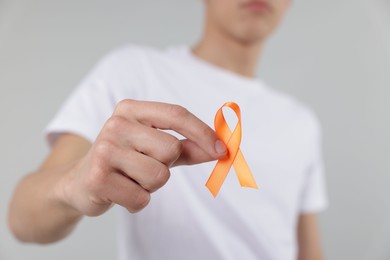 Photo of Multiple Sclerosis awareness. Man with orange ribbon on light grey background, closeup