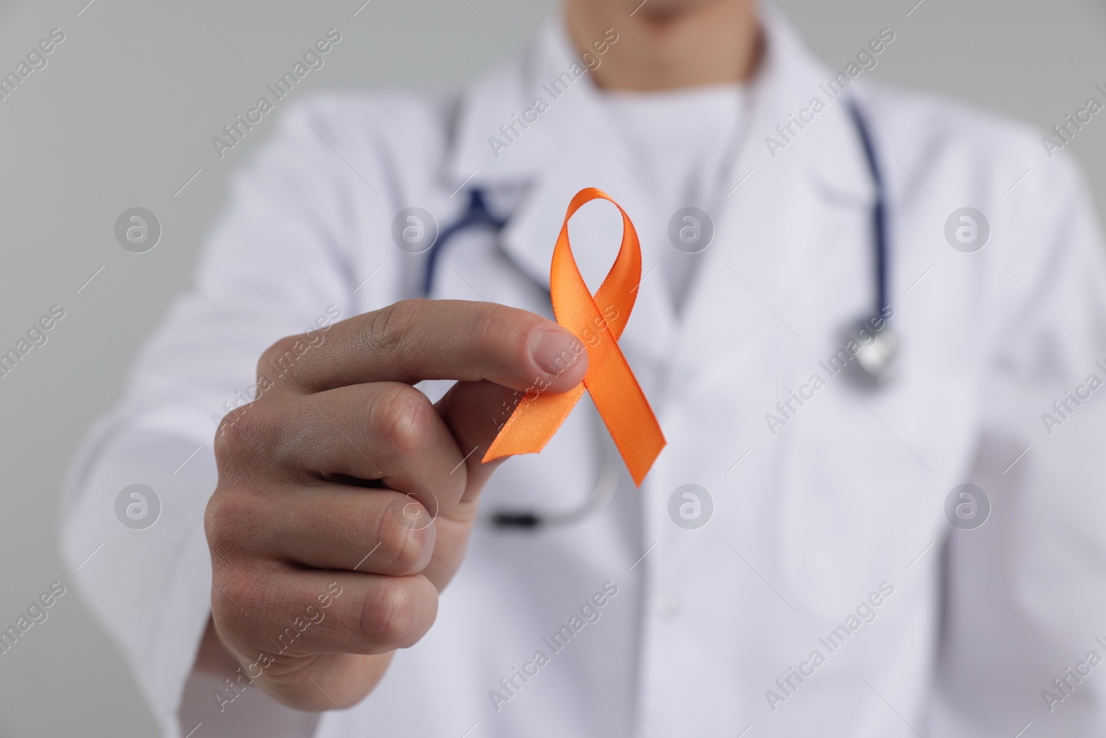 Photo of Multiple Sclerosis awareness. Doctor with orange ribbon on light grey background, closeup