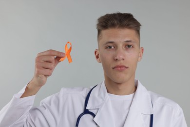 Photo of Multiple Sclerosis awareness. Doctor with orange ribbon on light grey background