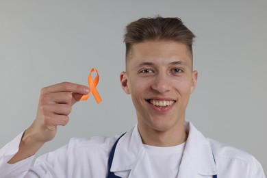 Photo of Multiple Sclerosis awareness. Doctor with orange ribbon on light grey background