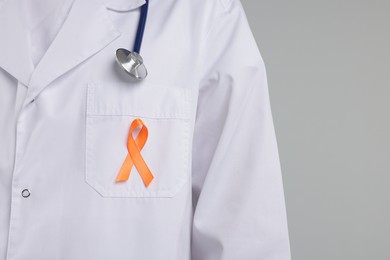 Photo of Multiple Sclerosis awareness. Doctor with orange ribbon on light grey background, closeup