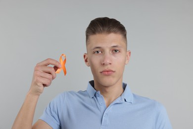 Photo of Multiple Sclerosis awareness. Man with orange ribbon on light grey background