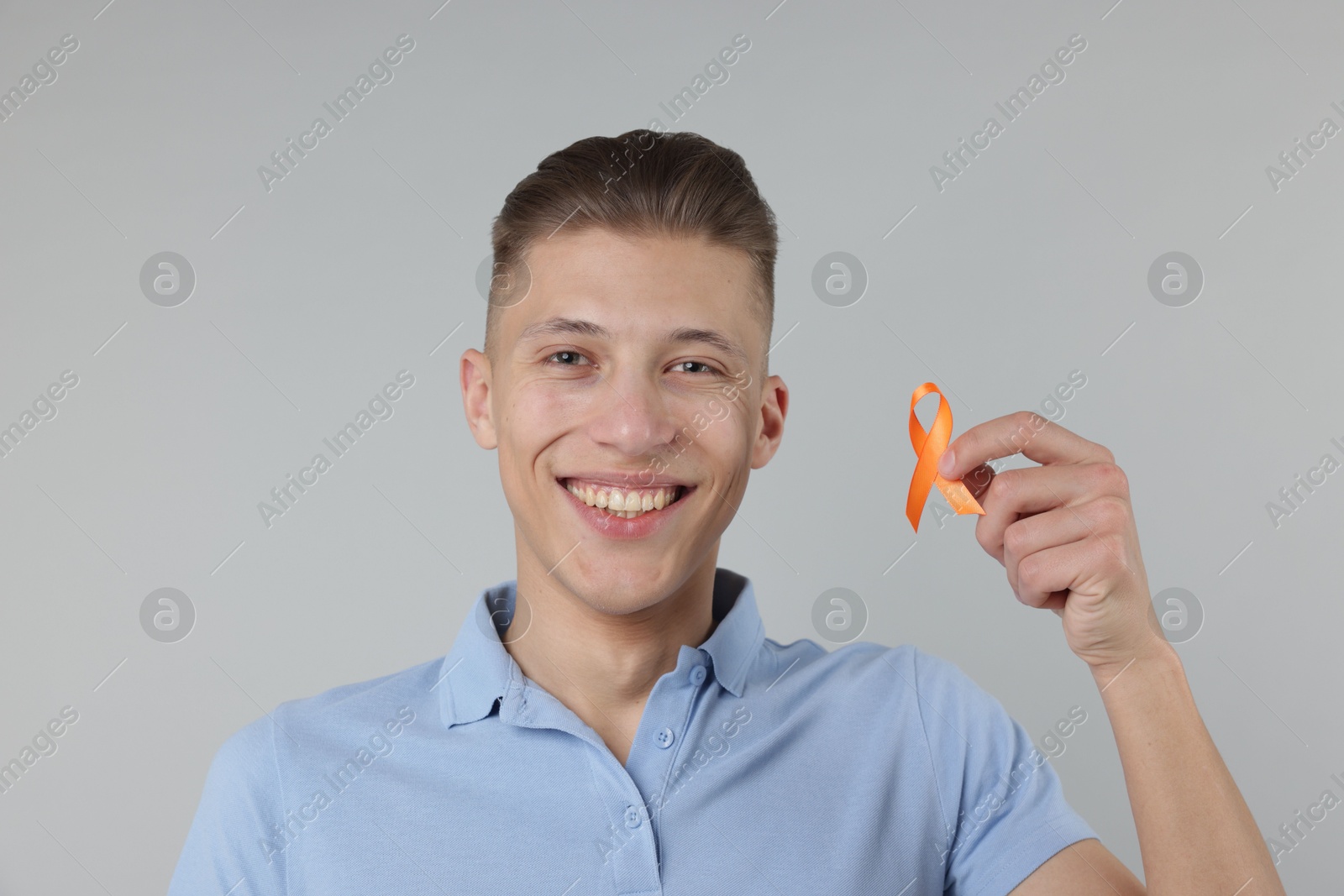 Photo of Multiple Sclerosis awareness. Man with orange ribbon on light grey background