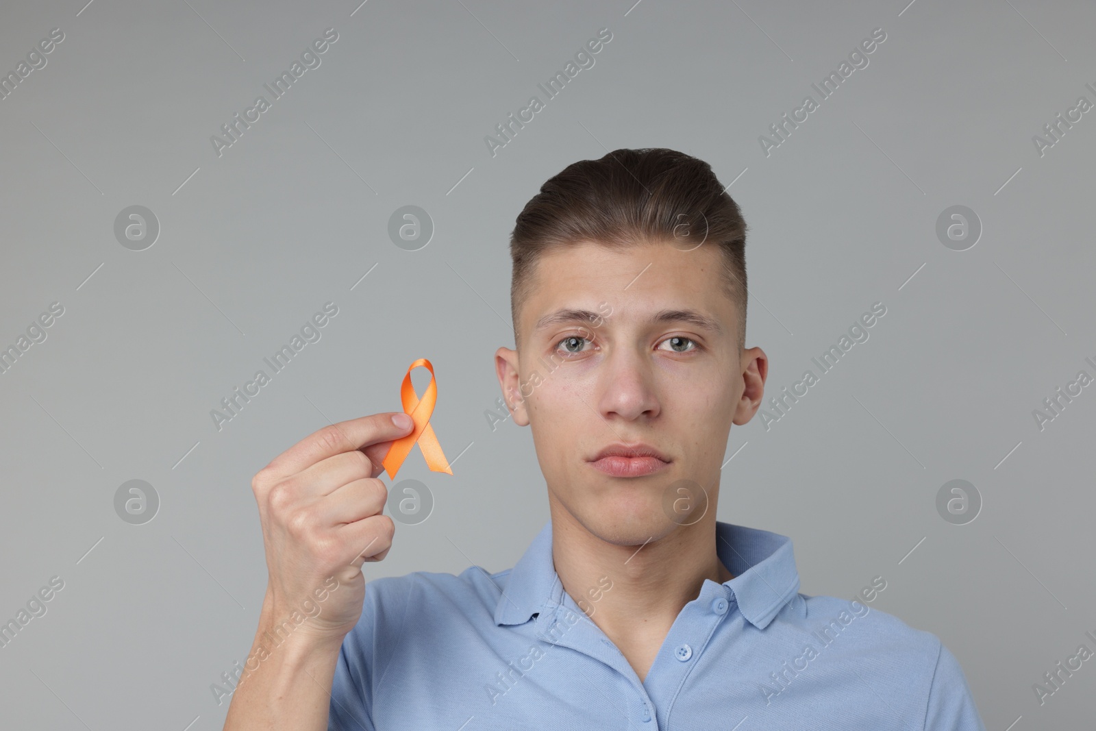 Photo of Multiple Sclerosis awareness. Man with orange ribbon on light grey background