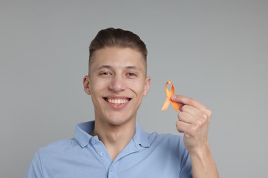 Photo of Multiple Sclerosis awareness. Man with orange ribbon on light grey background