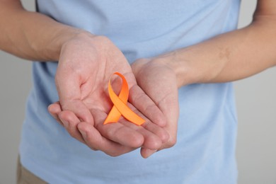 Photo of Multiple Sclerosis awareness. Man with orange ribbon on light grey background, closeup