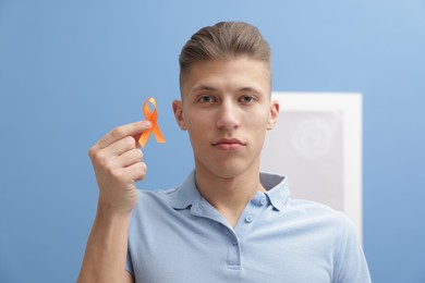 Photo of Multiple Sclerosis awareness. Man with orange ribbon indoors