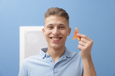 Photo of Multiple Sclerosis awareness. Man with orange ribbon indoors