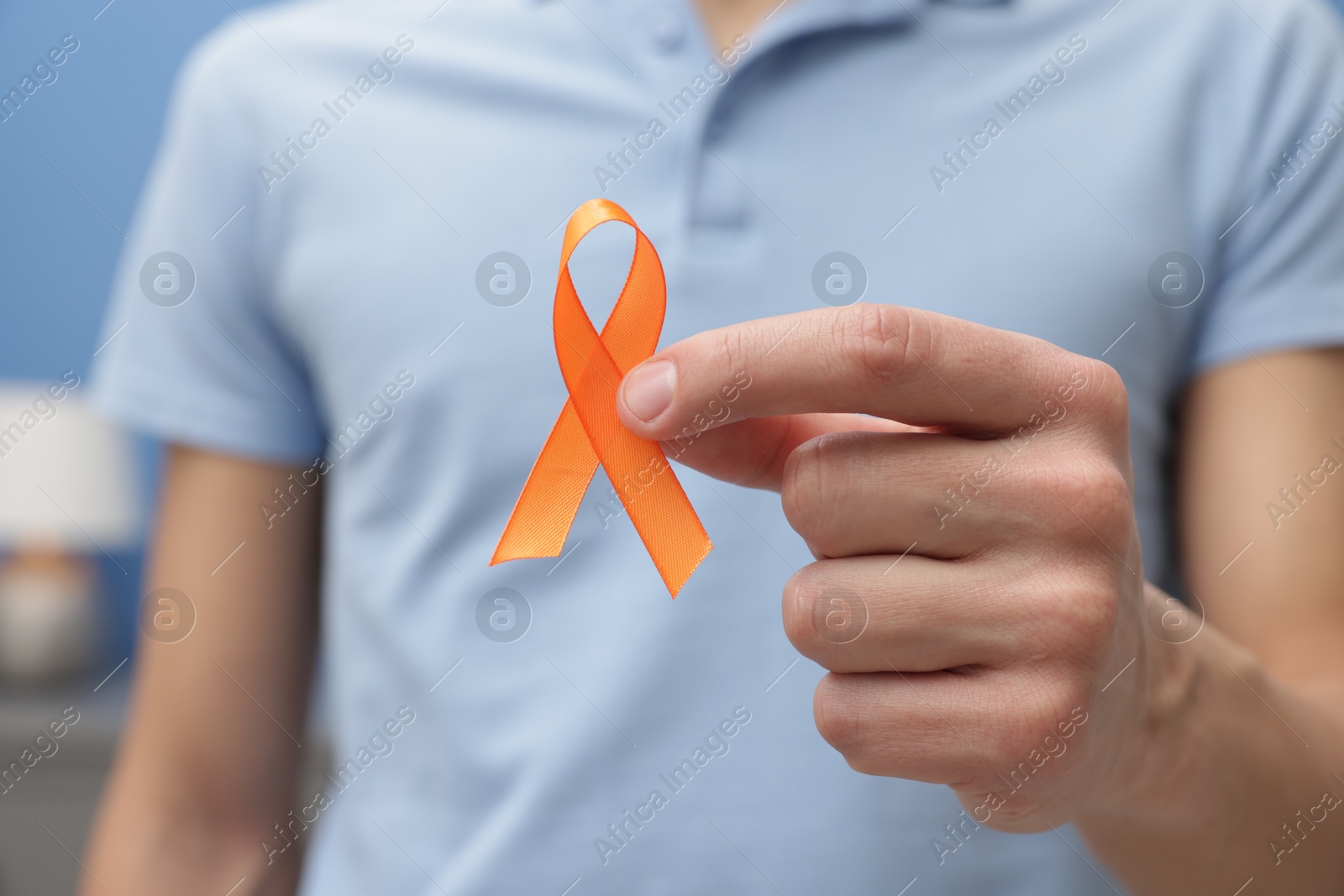 Photo of Multiple Sclerosis awareness. Man with orange ribbon indoors, closeup