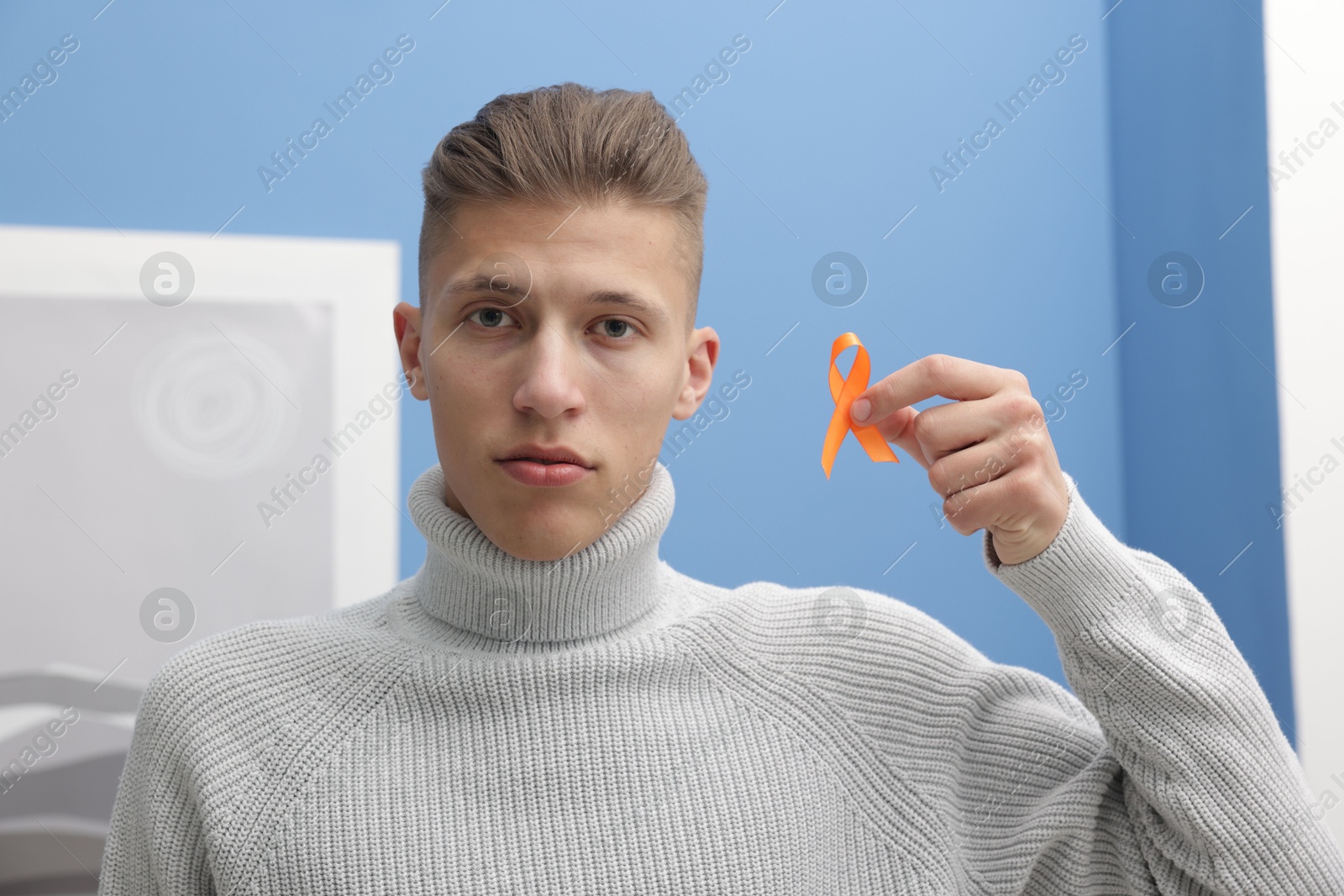 Photo of Multiple Sclerosis awareness. Man with orange ribbon indoors