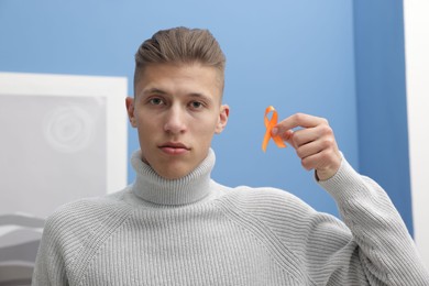 Photo of Multiple Sclerosis awareness. Man with orange ribbon indoors