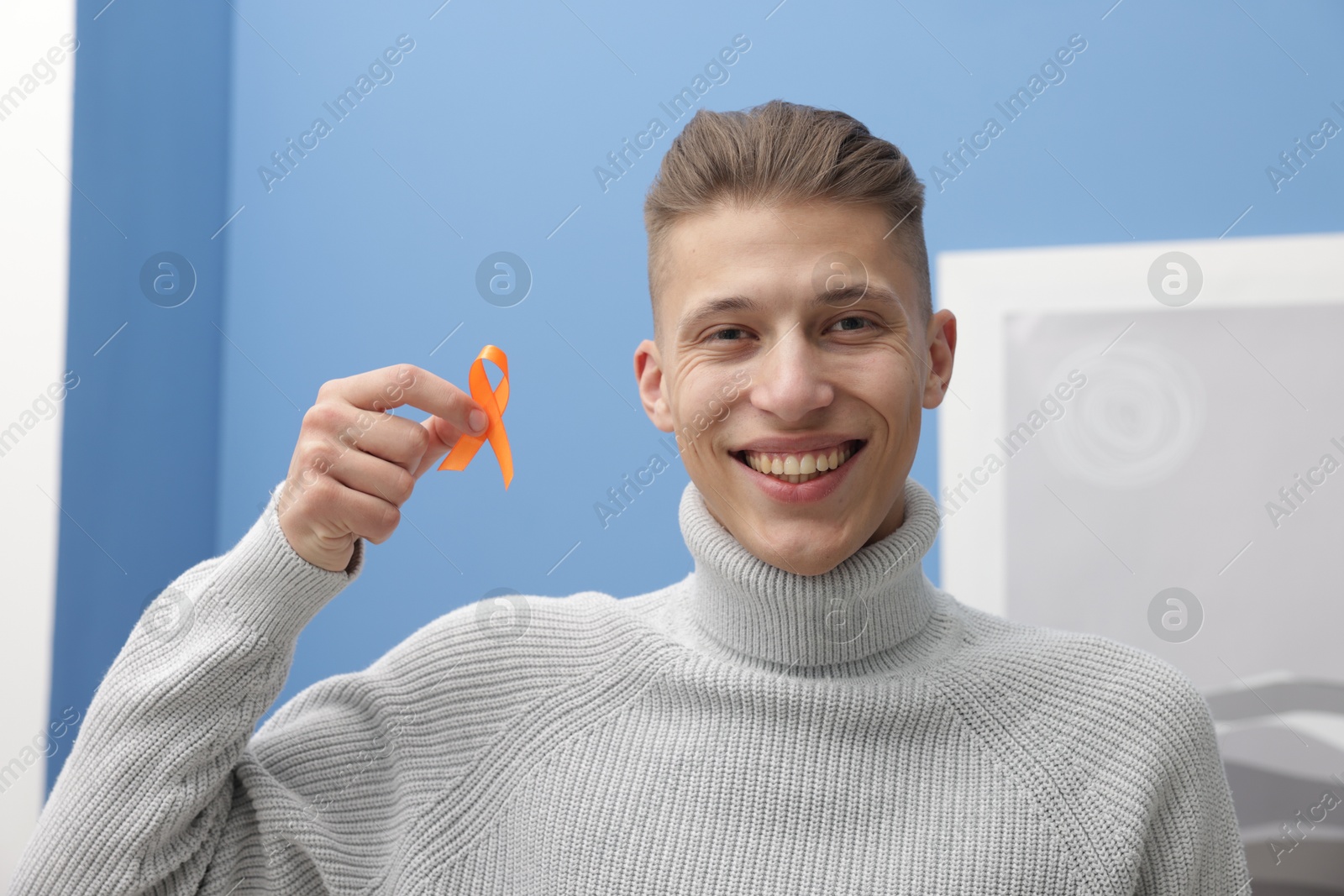 Photo of Multiple Sclerosis awareness. Man with orange ribbon indoors