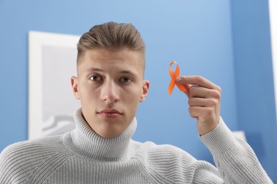 Photo of Multiple Sclerosis awareness. Man with orange ribbon indoors