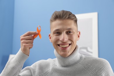 Photo of Multiple Sclerosis awareness. Man with orange ribbon indoors