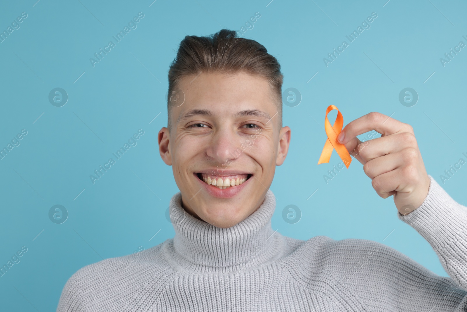 Photo of Multiple Sclerosis awareness. Man with orange ribbon on light blue background