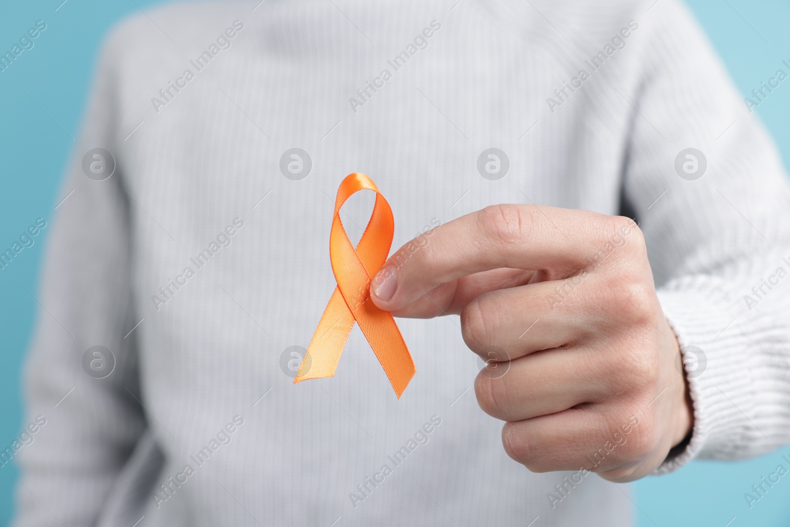 Photo of Multiple Sclerosis awareness. Man with orange ribbon on light blue background, closeup