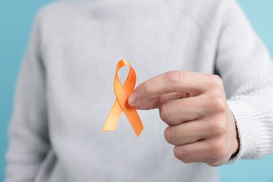 Photo of Multiple Sclerosis awareness. Man with orange ribbon on light blue background, closeup