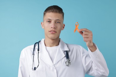 Photo of Multiple Sclerosis awareness. Doctor with orange ribbon on light blue background