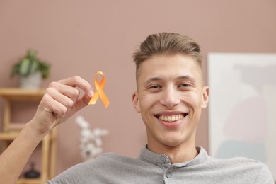 Photo of Multiple Sclerosis awareness. Man with orange ribbon indoors