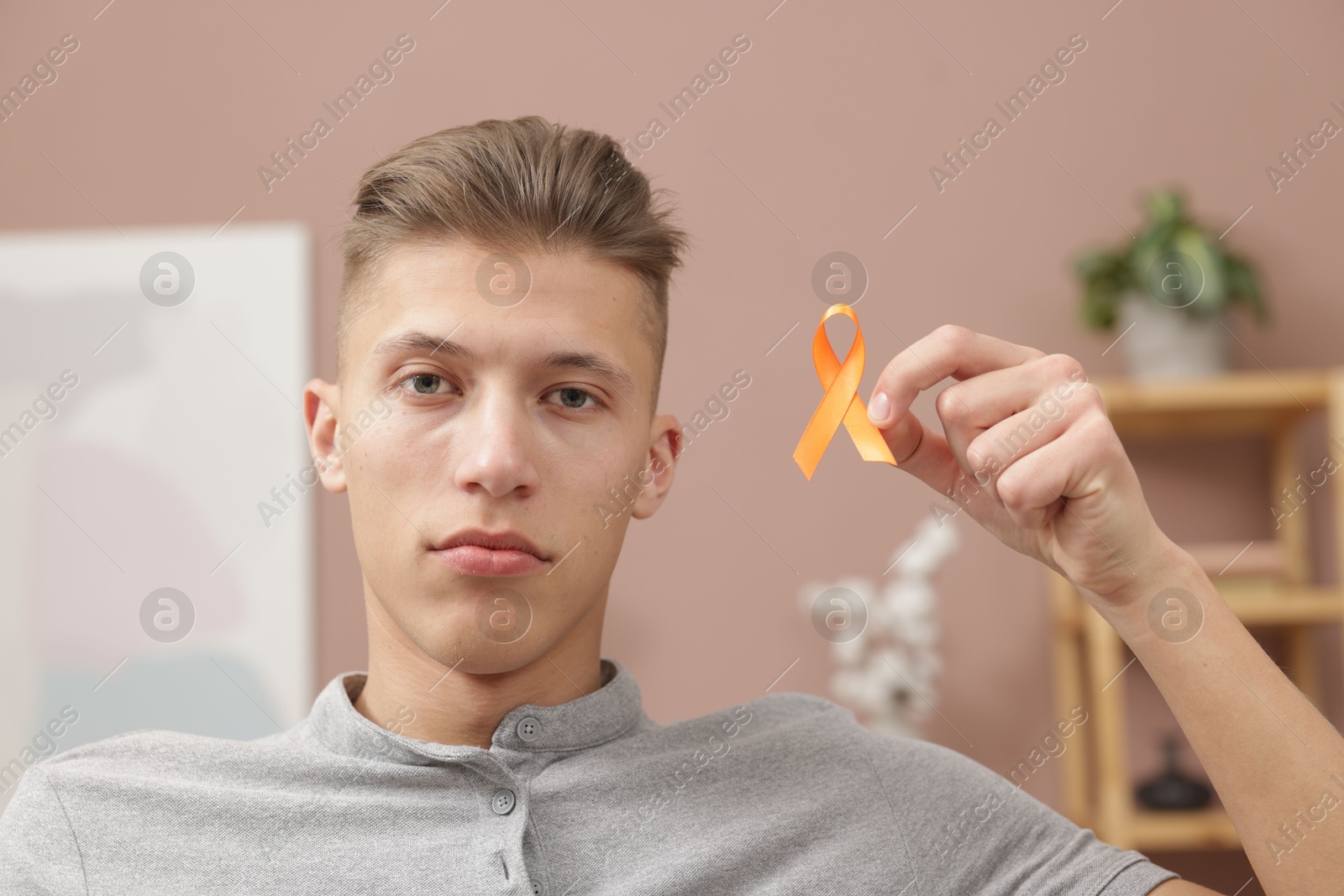 Photo of Multiple Sclerosis awareness. Man with orange ribbon indoors