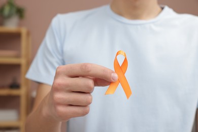 Photo of Multiple Sclerosis awareness. Man with orange ribbon indoors, closeup