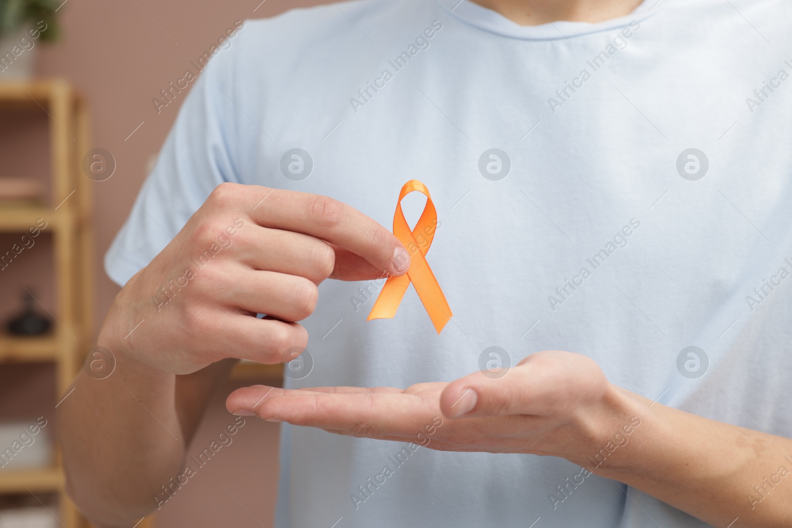 Photo of Multiple Sclerosis awareness. Man with orange ribbon indoors, closeup