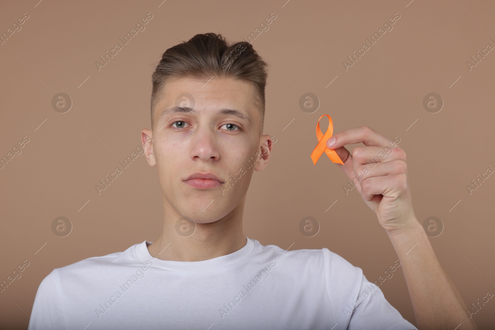 Photo of Multiple Sclerosis awareness. Man with orange ribbon on brown background