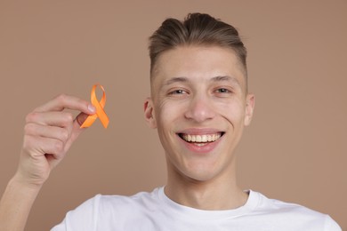 Photo of Multiple Sclerosis awareness. Man with orange ribbon on brown background