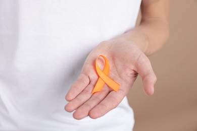 Photo of Multiple Sclerosis awareness. Man with orange ribbon on brown background, closeup