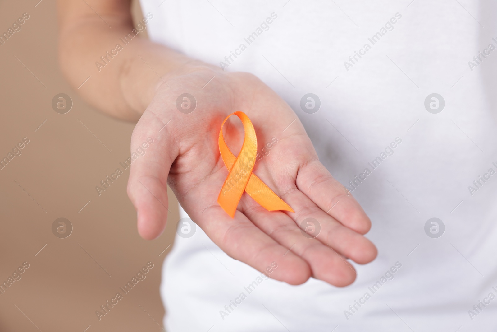 Photo of Multiple Sclerosis awareness. Man with orange ribbon on brown background, closeup