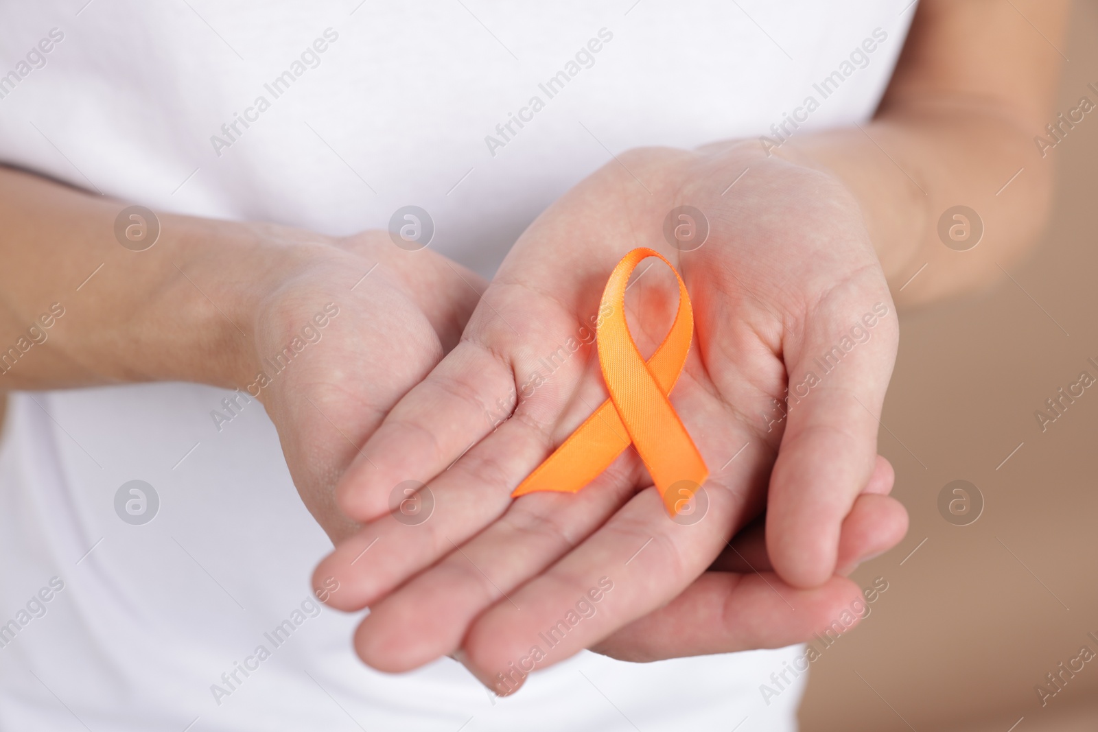 Photo of Multiple Sclerosis awareness. Man with orange ribbon on brown background, closeup