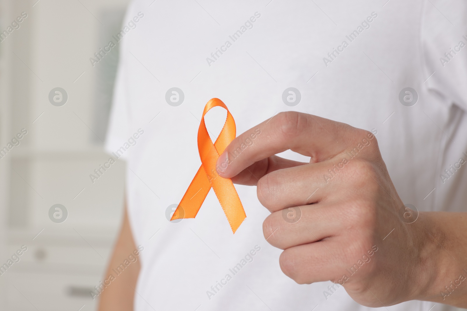 Photo of Multiple Sclerosis awareness. Man with orange ribbon indoors, closeup