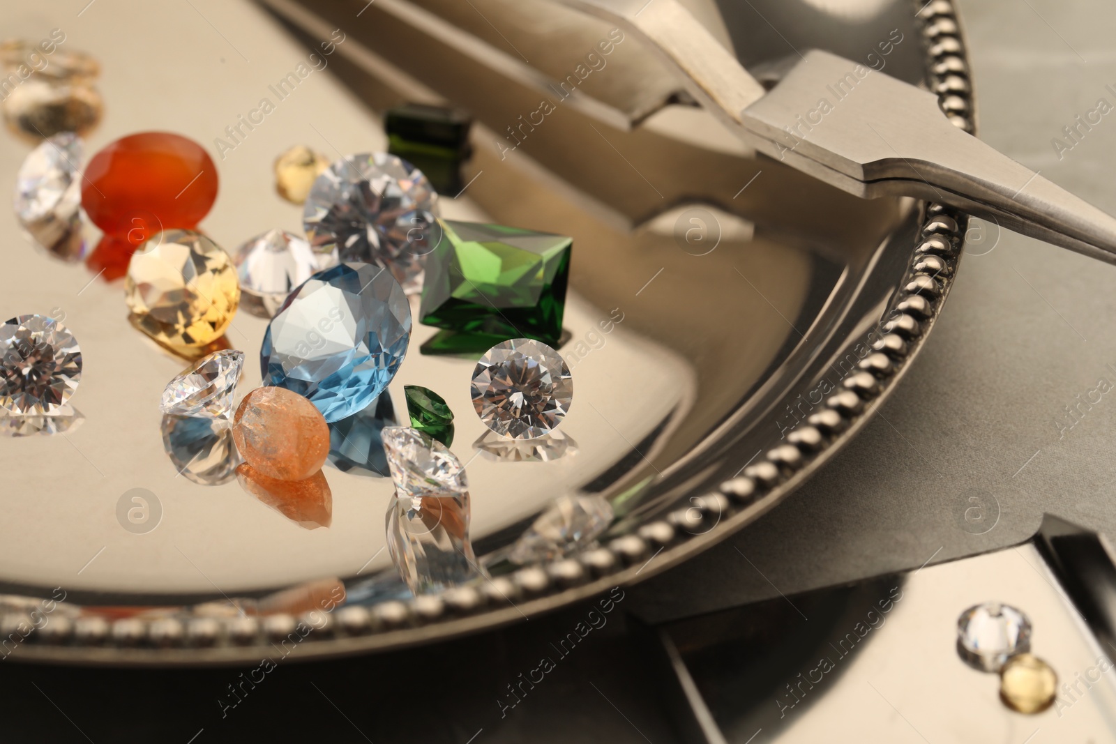 Photo of Tray with beautiful gemstones on light table, closeup