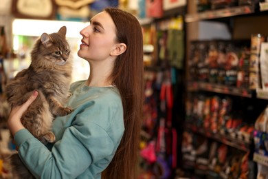 Photo of Happy woman with her cute cat in pet shop. Space for text