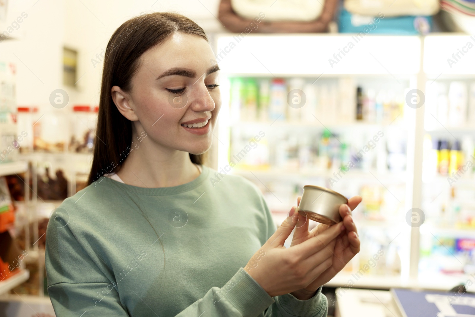 Photo of Woman with canned food in pet shop. Space for text