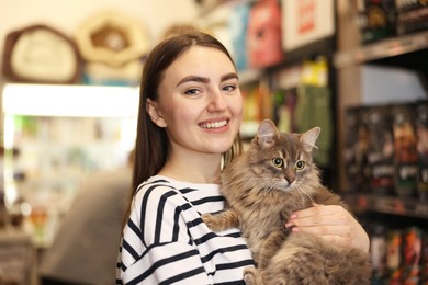 Photo of Woman with her cute cat in pet shop