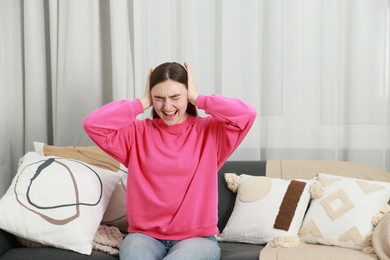 Photo of Frustrated woman covering her ears from loud noise at home