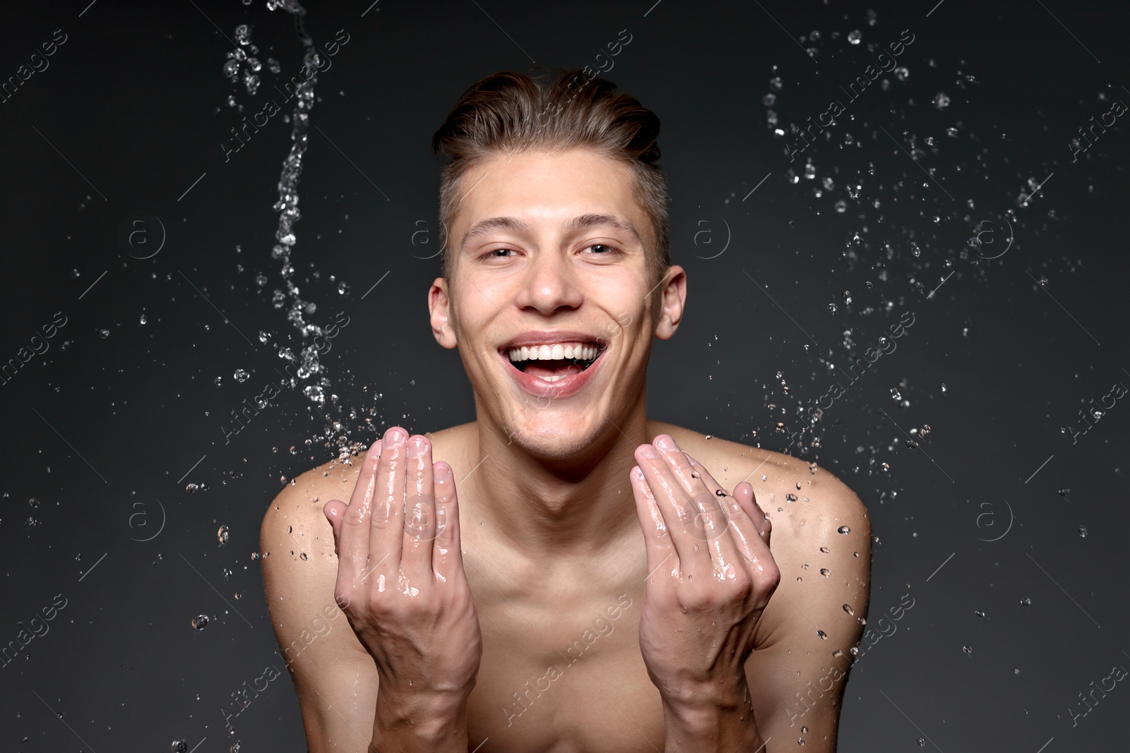 Photo of Smiling man washing his face on black background