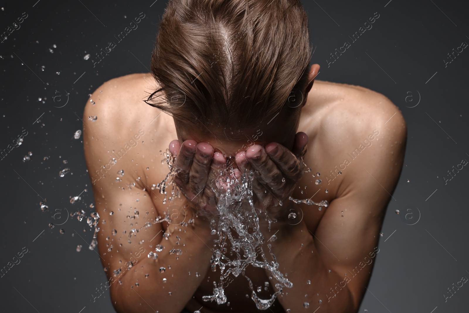 Photo of Man washing his face on black background