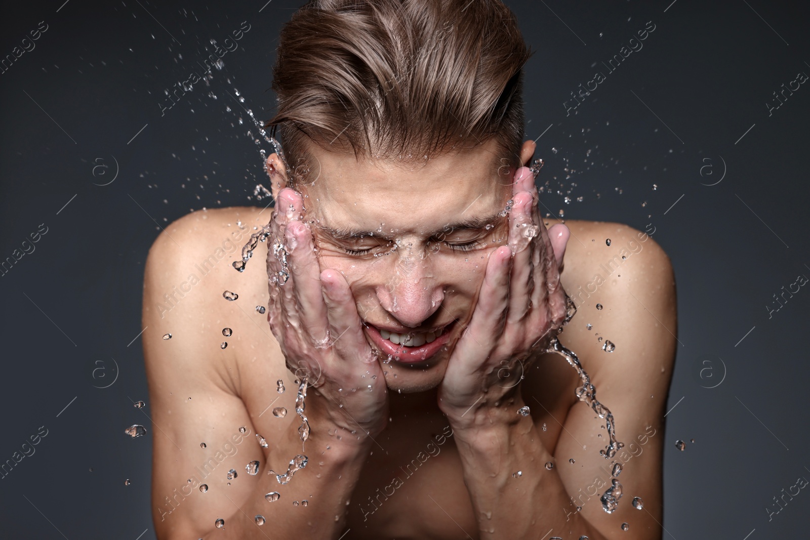 Photo of Smiling man washing his face on black background