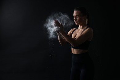 Photo of Woman clapping hands with talcum powder before training on black background, space for text