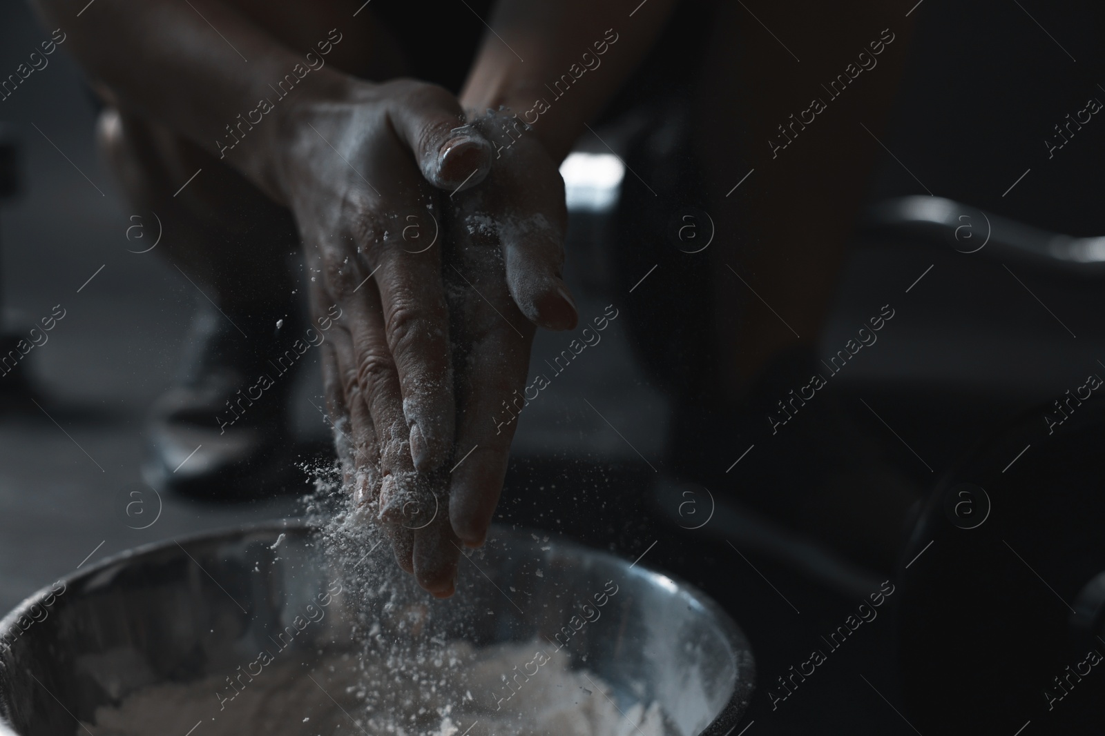 Photo of Woman applying talcum powder onto her hands above bowl before training in gym, closeup