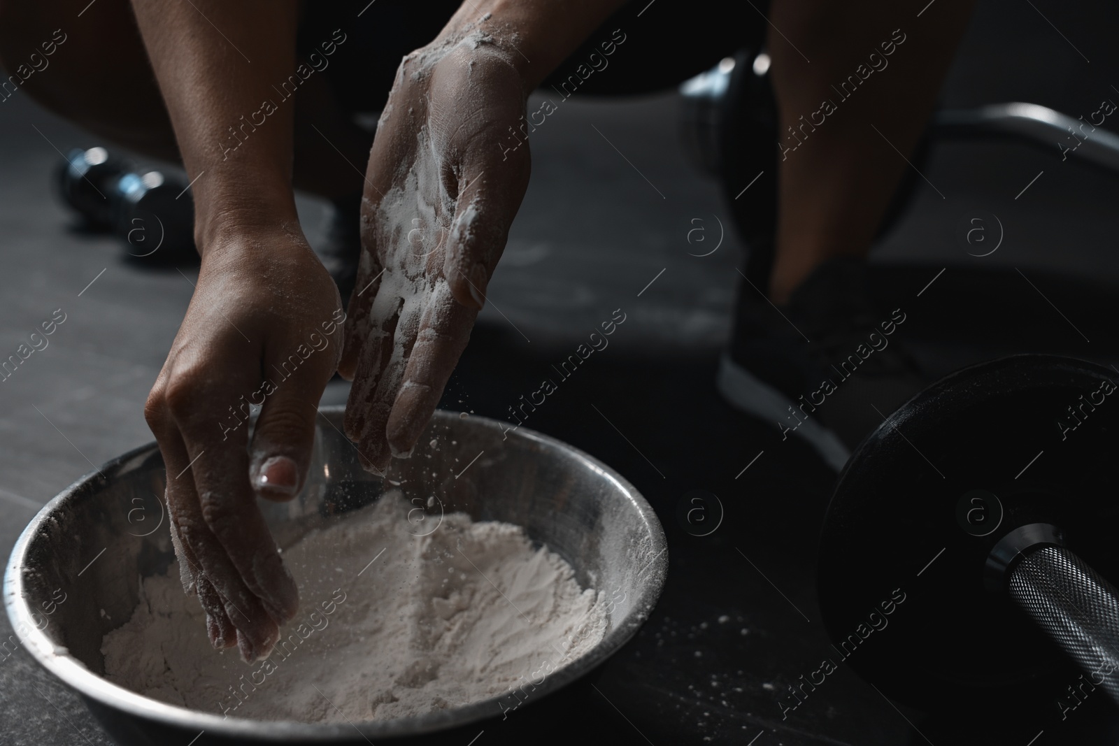 Photo of Woman applying talcum powder onto her hands above bowl before training in gym, closeup