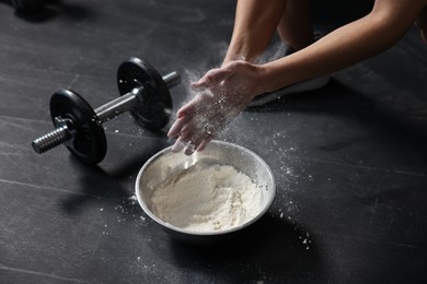 Photo of Woman clapping hands with talcum powder above bowl before training in gym, closeup