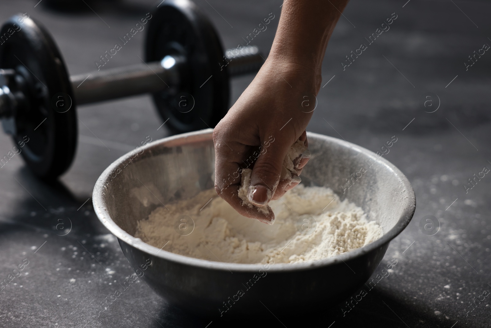 Photo of Woman applying talcum powder onto her hands above bowl before training in gym, closeup