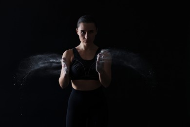 Photo of Woman clapping hands with talcum powder before training on black background